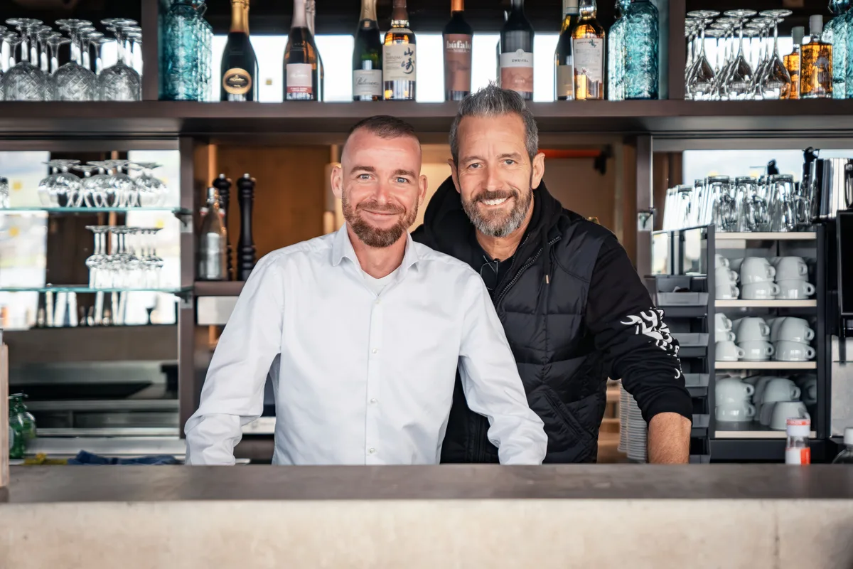 Geschäftsführer Maik Waskowski (links) und Pächter Päde Hofstetter freuen sich auf den 28. November. Geschäftsführer Maik Waskowski und Pächter Päde Hofstetter stehen im Seerestaurant hinter der Bar.